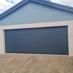 Grey sectional garage door with cream rendered garage and duck blue roofing