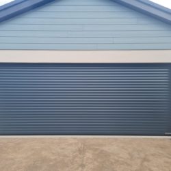 Grey sectional garage door with cream rendered garage and duck blue roofing