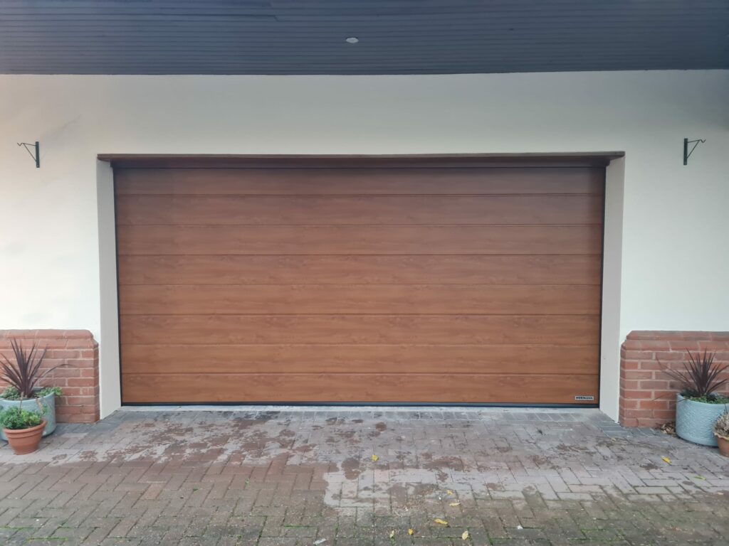 Up and over garage door in a oak finish with surrounding rendered cream walls