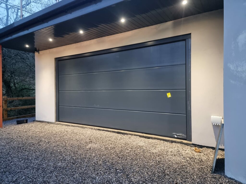 Black sectional garage door with surrounded cream rendered wall